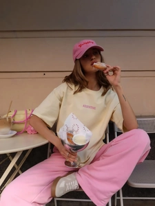 Dettaglio della t-shirt in cotone giallo chiaro con stampa rosa e cappellino da baseball