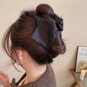 Polka dot fabric bow hair claw clip styled on woman's hair showing secure hold