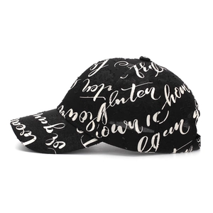 Close-up of distressed black baseball cap with white graffiti handwriting and torn edges