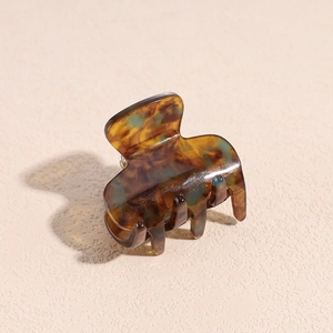 Detailed close-up of tortoise shell pattern hair claw clip with glossy amber finish