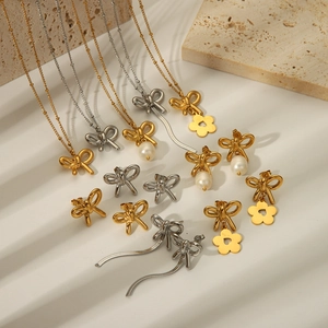 Golden and silver bow necklace and earring jewelry set on a textured surface