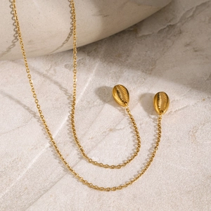 Close-up of 18k gold plated stainless steel layered necklace with shell pendants on marble
