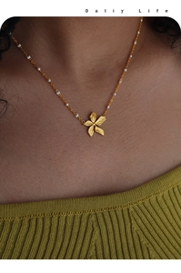 Dettaglio della collana con pendente a petalo in oro 18k e perle bianche sottili