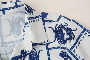 Close-up of lightweight white shirt collar with detailed blue crab print and buttons