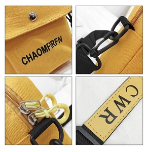 Detail of yellow canvas crossbody bag featuring buckle closure and dual zipper pulls