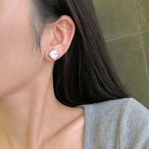Close-up of a square-cut sparkling zircon earring in a classic silver four-prong setting