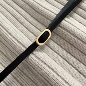 Elegant knit top features a black leather belt with a golden oval buckle accessory