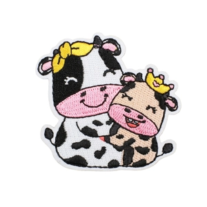 Cute embroidered cartoon cow and calf patch with crown on a clean white background