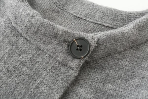 Dettaglio macro di un cardigan in maglia grigia con bottone tartarugato scuro testurizzato