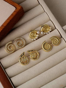 Macro detail of 18k gold plated pearl spiral stud earrings in a beige velvet jewelry box