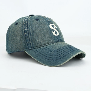 Detailed close-up of white letter S embroidery on navy washed denim baseball cap texture