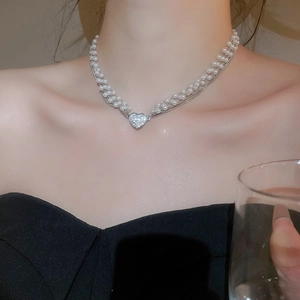 Detail of multi-layer pearl necklace with a sparkling heart pendant worn by a model