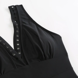Detail of black V-neck swimsuit with laser-cut square cutouts and pleated fabric texture