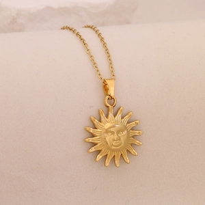 Macro detail of a golden sun face pendant necklace with polished metallic finish