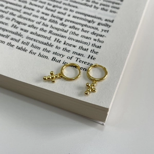 Minimalist S925 sterling silver gold beaded cross hoop earrings displayed on a book page