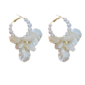 Elegant gold hoop earrings with white pearls and shell-shaped petals on white background