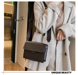 Detail of dark brown matte leather crossbody bag with wide strap on model