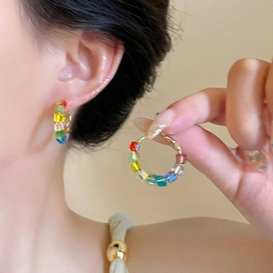 Détail des boucles d'oreilles créoles avec fleurs perlées colorées et alliage doré