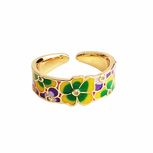 Detalle macro de anillo dorado ajustable con patrones de flores de cinco pétalos esmaltados