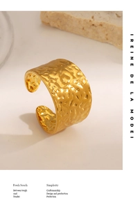 Macro detail of wide gold hammered texture open ring on a minimalist stone background