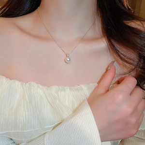 Detail of round pearl necklace with sparkling zircon inlay worn by a model in elegant style