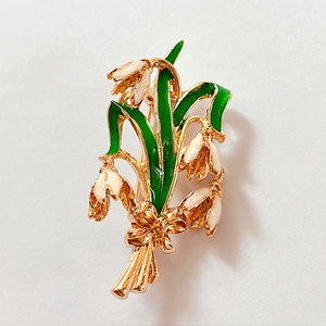 Detail of lily of the valley brooch with white enamel petals and gold bow accent