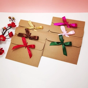 Flat lay of kraft paper envelopes with colorful ribbon bows on a pink background