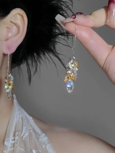 Macro detail of long tassel earrings featuring iridescent glass beads and silver chain link