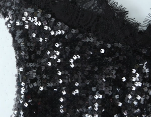 Détail macro de paillettes noires et dentelle de cils sur une robe de soirée