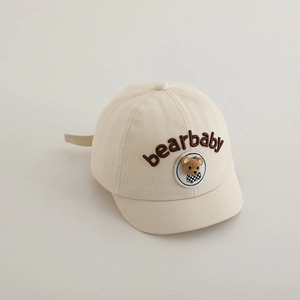 Dettaglio cappello beige per bambini con patch orsetto 3D e ricami fini