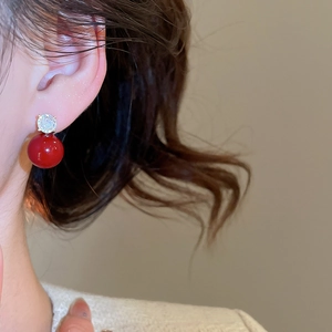 Macro shot of elegant red pearl earrings with sparkling crystal accents on a model