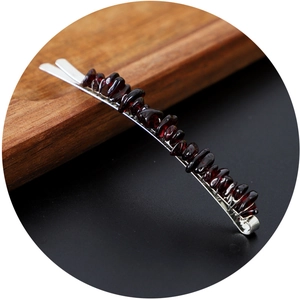 Silver hair clip with dark red natural crystal stones on a minimalist wooden background