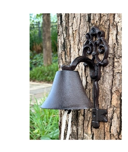 Detail of vintage cast iron doorbell with key motif mounted on a tree in garden