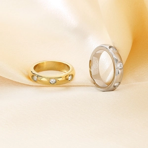 Detail of gold and silver wide band rings with inlaid zircons on champagne satin