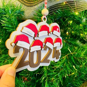 2024 Wooden Christmas ornament featuring a Santa hat and paw print on a Xmas tree