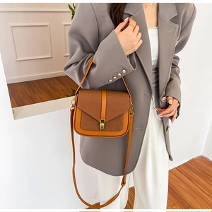 Detail of a brown leather patchwork crossbody saddle bag showing metal buckle and texture