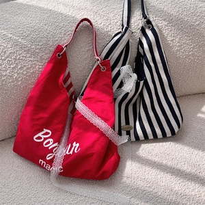 Détail de sacs cabas en toile avec rayures, bordures en dentelle et broderie Bonjour