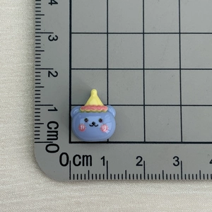 Close-up of small blue resin bear with yellow hat on measuring mat, 2cm size detail
