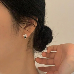 Detail of vintage sterling silver bow earrings with black oval stone and small pearls