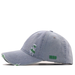 Close-up of distressed light blue denim baseball cap with green 1989 embroidery detail