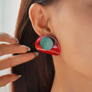 Detail view of red and green acrylic geometric drop earrings worn by a model
