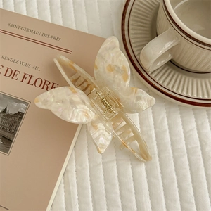 Detail of elegant acetate butterfly hair claw clip on quilted fabric with a French cafe vibe