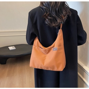 Detail of caramel nylon hobo bag featuring V-shaped stitching and exterior pocket