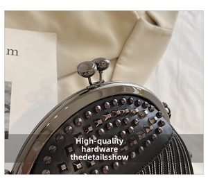 Detailansicht der schwarzen Clutch mit Metallnieten, Fransenketten und Kugelverschluss