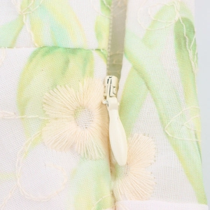 Close-up of invisible zipper on white floral embroidered midi dress with leaf print