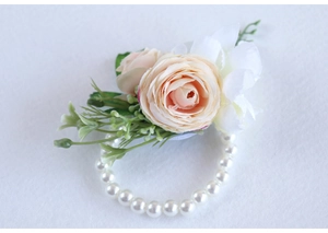 Detail of faux pink rose wrist corsage with white petals and pearl elastic bracelet