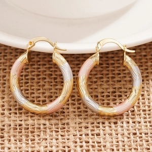 Macro shot of triple-tone hoop earrings with spiral texture in gold, silver, and rose gold