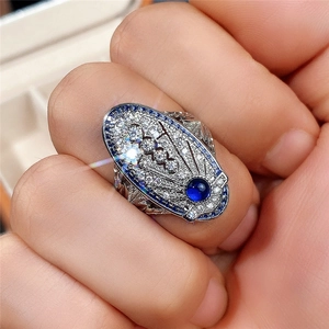 Anillo estilo Art Deco con piedra azul y pavé de diamantes lucido en la mano