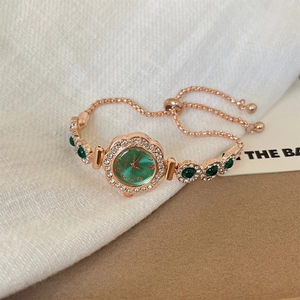 Detailansicht der roségoldenen Armbanduhr mit smaragdgrünem Zifferblatt und Strass