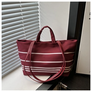 Close-up of burgundy canvas tote bag with white horizontal stripes in natural sunlight